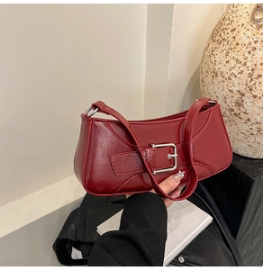 Detailed view of dark red faux leather baguette bag featuring silver metal buckle accents