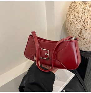 Detail of burgundy baguette bag with large silver buckle on glossy leather surface