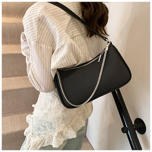 Close-up of black textured leather bag with silver chain detail on model shoulder