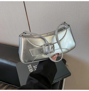 Close-up of metallic silver baguette bag with buckle strap on a black book prop