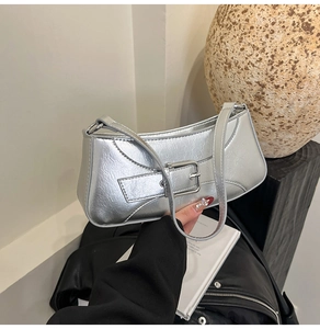 Detail of silver baguette bag featuring crinkled metallic texture and buckle design