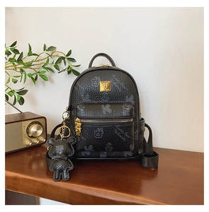Close-up of black leather bear print backpack with golden logo and bear charm detail