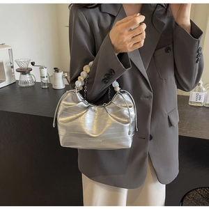 Detailed view of silver pleated dumpling bag with bead handle and crocodile texture