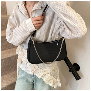 Detail of black woven texture and silver chain on minimalist shoulder underarm bag