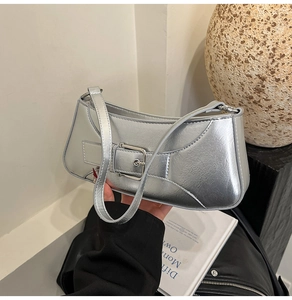 Detail of metallic silver baguette bag featuring a large square buckle and textured finish
