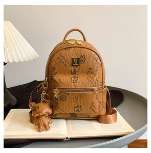 Detail of vintage brown leather backpack with bear prints and a teddy bear charm
