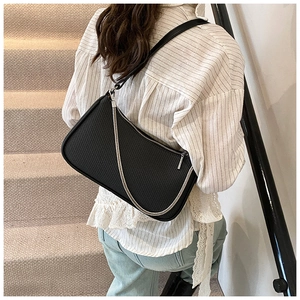 Detail of black woven shoulder bag with silver chain strap shown in a lifestyle setting