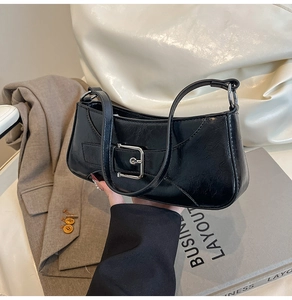 Detail of black wrinkled patent leather shoulder bag with silver buckle and zipper