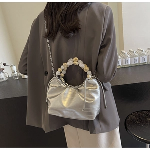 Close-up of silver pleated dumpling bag with chunky beaded handle and metal chain strap