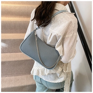 Detail of blue woven shoulder bag texture with silver chain and leather strap on model