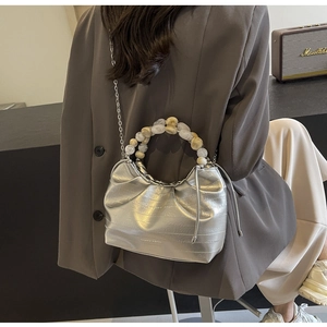 Detail of silver metallic pleated bag featuring a beaded handle and chain strap