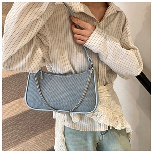 Detail of light blue baguette bag featuring fine diagonal twill texture and silver chain