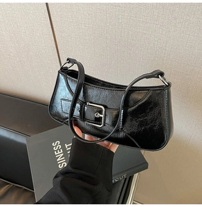 Close-up of a black patent leather shoulder bag with a silver buckle and glossy finish