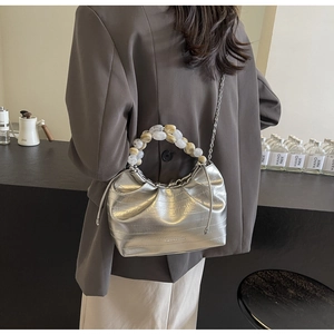 Detail of silver pleated crossbody bag featuring marble bead handle and metallic chain