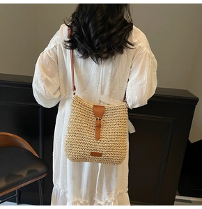 Detail of hand-woven straw bag with adjustable brown leather strap and buckle