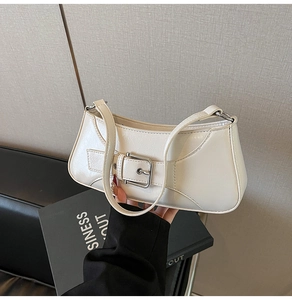 Close-up of a white glossy underarm bag with a decorative buckle and silver hardware