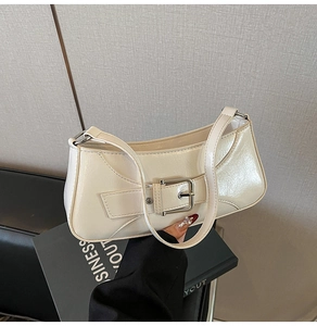 Detail view of glossy cream underarm bag with silver metal buckle and patent finish