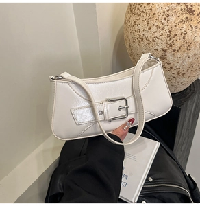 Detail view of cream white faux leather baguette bag with silver buckle and slim strap