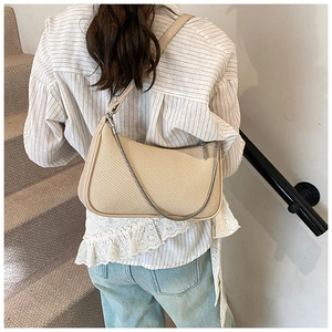 Detailed texture of beige woven crescent bag with leather trim and silver chain