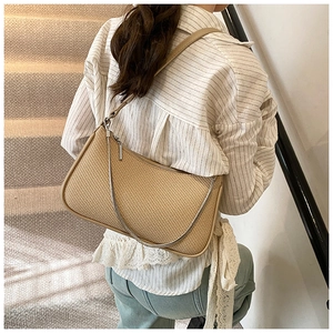 Detail of khaki woven straw underarm bag with leather trim and silver chain strap