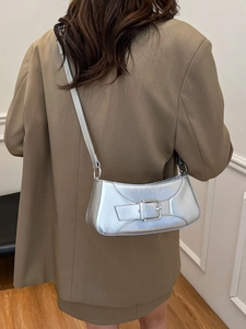 Metallic silver crescent shoulder bag with belt buckle detail worn with a blazer