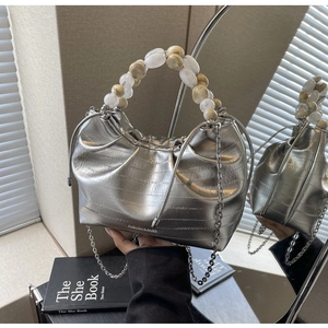 Detail of silver pleated dumpling bag with beaded handle and fine metal chain strap