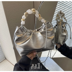 Detail of silver pleated cloud bag with elegant marble bead handle and metallic finish