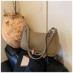 Close-up of woven texture underarm bag with silver chain detail in olive green finish