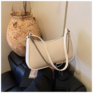 Detail view of cream woven crescent bag with leather trim and silver chain accent