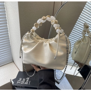 Detail of ruched dumpling bag with beaded handle and marble resin beads on white leather