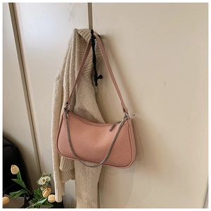 Detailed view of pink woven baguette bag featuring silver chain and leather shoulder strap