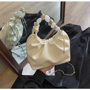 Detail of cream pleated cloud bag with marble bead handle and faux crocodile texture