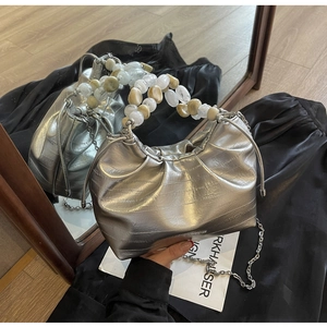 Detail of silver pleated dumpling bag featuring marble bead handle and chain strap