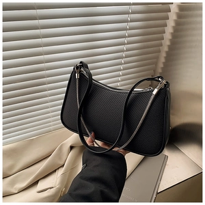 Close-up of black woven shoulder bag with metallic chain detail and zipper texture