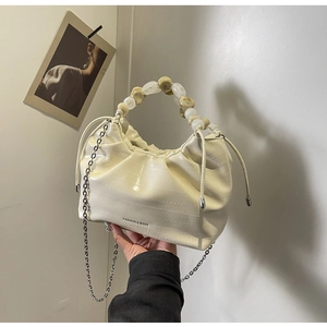 Detail of cream dumpling bag with beaded handle, silver chain and drawstring texture
