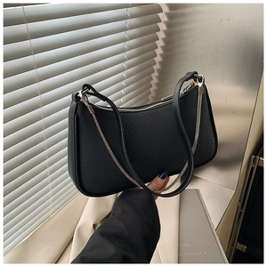 Detail of black woven shoulder bag featuring a silver chain strap and sleek zipper
