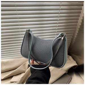 Close-up of blue-grey woven texture on women's underarm bag with silver chain detail