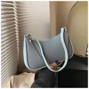 Detail showing woven light blue fabric texture and leather shoulder strap of baguette bag