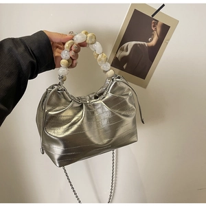 Detail of silver pleated cloud bag featuring large marble bead handle and metal chain