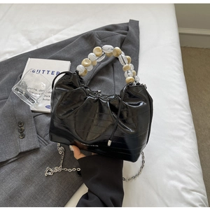 Detail of glossy pleated handbag with marble beaded handle and silver chain strap