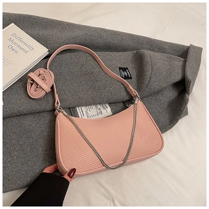 Detailed shot of pink textured baguette bag with silver chain on wool coat