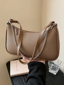 Brown woven baguette bag with silver chain strap shown in a stylish lifestyle setting