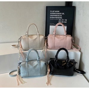 Detail of four colorful PU leather bowling bags with woven rope charms and embossed letters