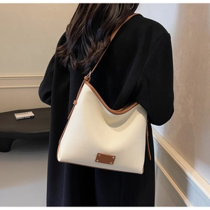 Side view of white textured tote bag with brown trim and adjustable strap on a model