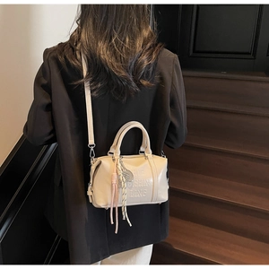 Detalle de bolso de cuero crema con relieve de Fashion Ling y borla decorativa elegante