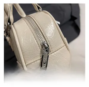 Macro view of silver KOSK zipper hardware and wrinkled cream leather on handbag