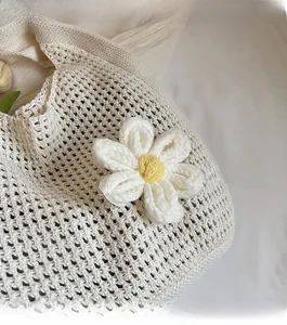 Détail d'un sac cabas en crochet crème fait main avec un ornement floral tricoté jaune