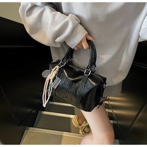 Detailed close-up of black glossy bowling bag with embossed letters and sports charms