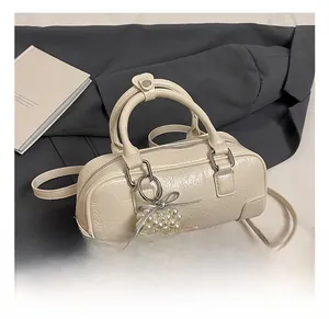 Close-up of cream white bowling bag with wrinkled patent leather texture and pearl charm