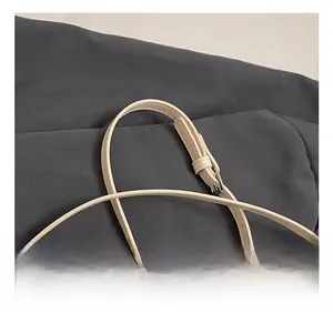 Detail of adjustable off-white embossed leather shoulder strap with silver metal buckle